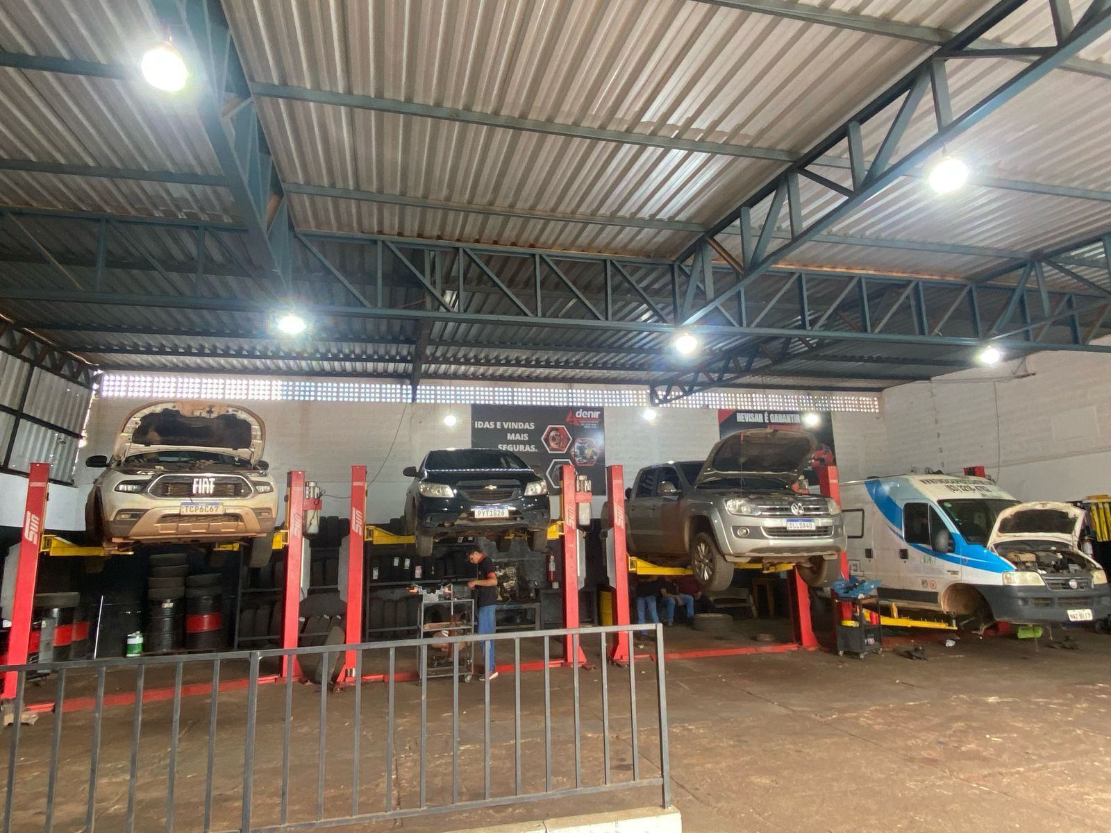 Interior da oficina da Adenir com veículos nos elevadores